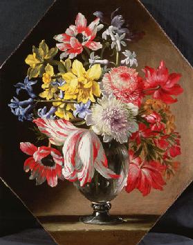 A Glass Vase of Flowers on a Stone Ledge Containing Tulips, Chrysanthemums, Roses and Bluebells
