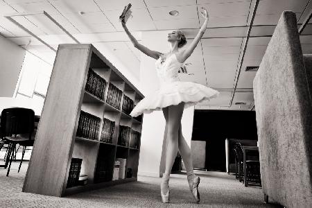 the Dreamer. ballerina on pointe shoes in the library reads a book holding it up