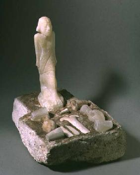 Implements and vessels on an altar-shaped slab with standing figure Egyptian
