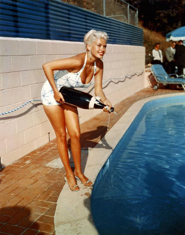 American Actress Jayne Mansfield with a bottle of champagne, near a swimming pool from English Photographer, (20th century)