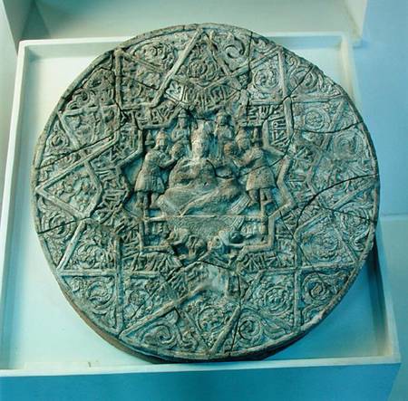 Sun disc depicting a king sitting cross-legged on a throne flanked by two angels in the centre, foun from Islamic School