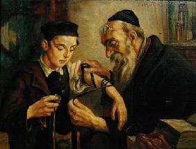 A Rabbi tying the Phylacteries to the arm of a boy