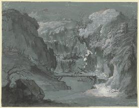 Tiefe Gebirgsschlucht mit einem Wasserfall, in der Mitte ein Steg, über den zwei Personen gehen