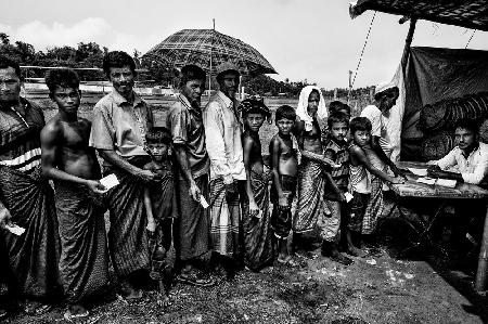 Rohingya refugees queuing to get some items to build their homes.