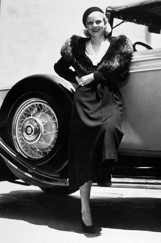 American Actress Jean Harlow posing near a car from 